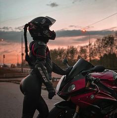 a person on a motorcycle wearing a helmet and holding onto the handlebars as the sun sets