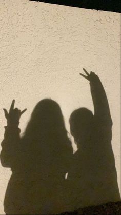 the shadow of two people holding their hands up