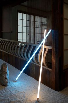 a light saber sitting on top of a white rug next to a stone statue in front of a window