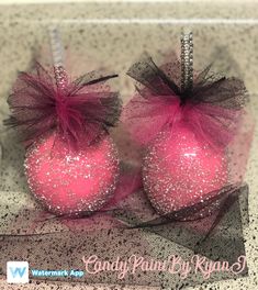 two pink ornaments with black and white bows on them are sitting on a counter top