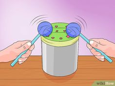 two hands holding spoons over a bucket filled with candy