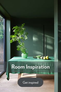 a room with a green table cloth on it and a potted plant in the corner