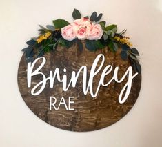 a wooden sign that says brinley rae with flowers on the top and below it