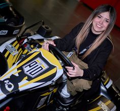 a woman sitting on top of a yellow and black motorbike in a garage