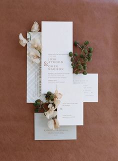 the wedding stationery is laid out on top of each other with flowers and greenery