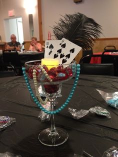 a table topped with a wine goblet filled with lots of candy and cards