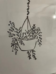 a drawing of a hanging basket with flowers in it on a white board, next to a pen and marker