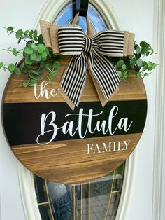 a wooden sign that says the battula family hanging from a door with a bow on it