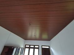 an empty room with wooden ceiling and windows