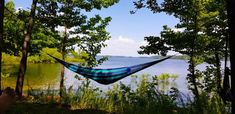 a hammock is hanging in the trees by the water's edge while someone takes a photo