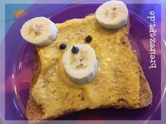 a piece of toast with bananas and cheese on it, topped with a bear face