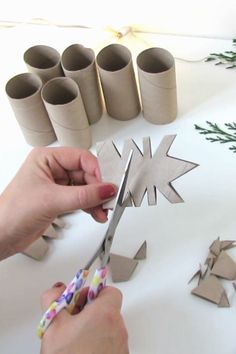 someone cutting out paper snowflakes on a table with scissors and other crafting supplies