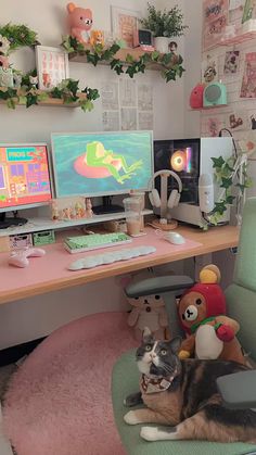 a cat laying on top of a green chair next to a desk with two monitors