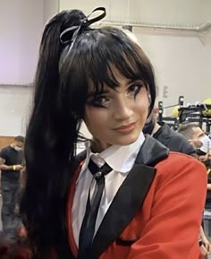 a woman with long black hair wearing a red jacket and tie