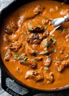 a skillet filled with meatballs and sauce on top of a gray countertop