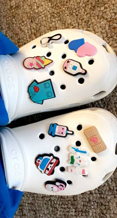 a pair of white shoes with stickers on them sitting on the floor next to a blue bag