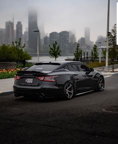 a black sports car parked in front of a cityscape on a cloudy day