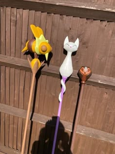 three different types of plastic flowers in front of a wooden fence, one is purple and the other is yellow