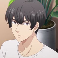 a young man with black hair and white shirt in front of a potted plant