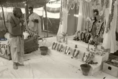 two men standing in front of a table with candles and garlands on it, surrounded by other items