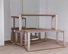 three wooden tables sitting in front of a mirror on top of a hard wood floor