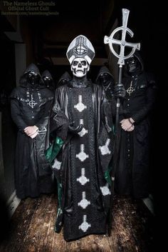 three people dressed in black with white crosses on their faces