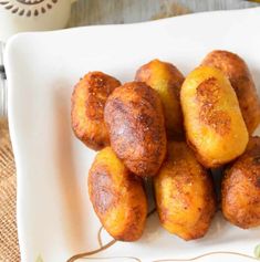 there is a white plate that has some fried food on it and two bananas in the background