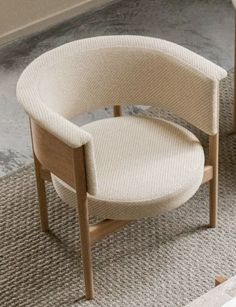 a white chair sitting on top of a carpeted floor next to a wooden table