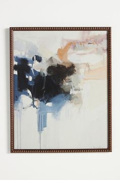 an abstract painting hangs on the wall in front of a white wall with a brown frame