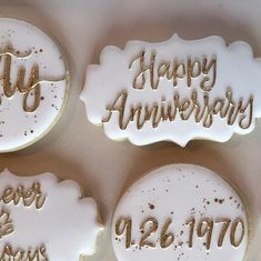 three decorated cookies that say happy anniversary and year in gold lettering on white frosting