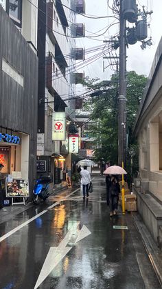 people walking down the street with umbrellas in the rain