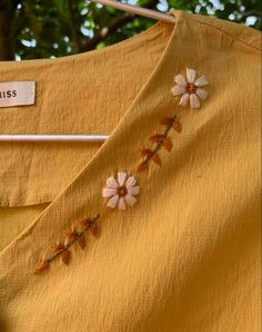 a yellow dress with white flowers on it and a name tag hanging from the back