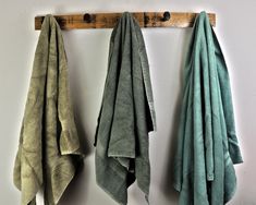 three green towels hanging on a wooden rack