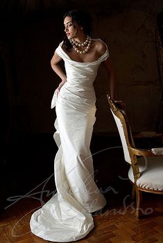 a woman in a white dress standing next to a chair