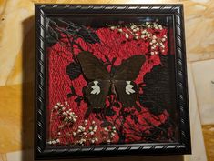 a black and white butterfly sitting on top of a red flowered cloth covered wall