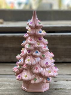 a pink ceramic christmas tree sitting on top of a wooden table