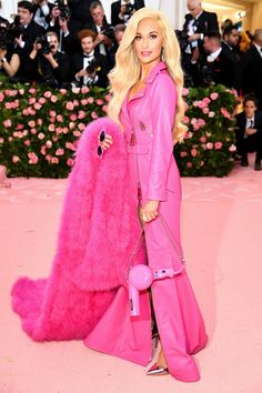 the blonde woman is dressed in pink and posing with her large fur coat on display