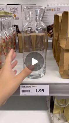 a person is pointing at some glass vases on a shelf in a store aisle