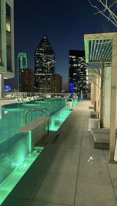 an empty swimming pool with city lights in the background