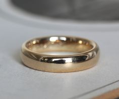 a gold wedding ring sitting on top of a counter next to a white object in the background