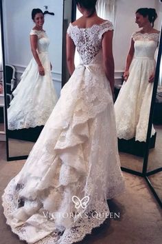 a woman standing in front of a mirror wearing a wedding dress with an open back