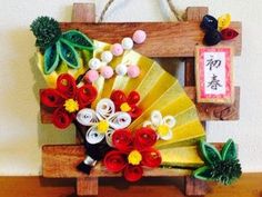 a wooden frame with flowers and other decorations on it, sitting on a table in front of a wall