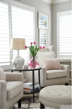 a living room with white furniture and pink flowers on the table in front of it