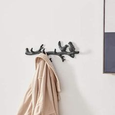 a coat rack with two coats hanging from it's sides next to a white wall