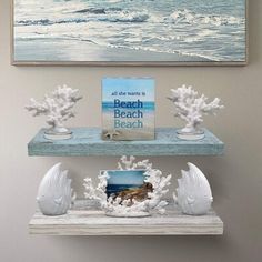 two white shelves with seashells on them in front of a painting and an ocean scene