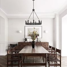 a dining room table with chairs and a vase filled with flowers on top of it