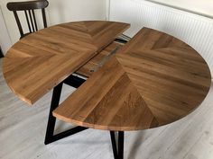 a wooden table with black metal legs and an upside down design on the top, sitting in a white room