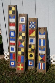 three pieces of wood are painted with different colors and designs on them, sitting in the grass