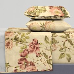 three pillows are stacked on top of each other in front of a bed with floral sheets