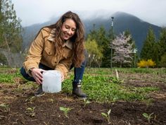 a woman kneeling down in the dirt with a plastic container